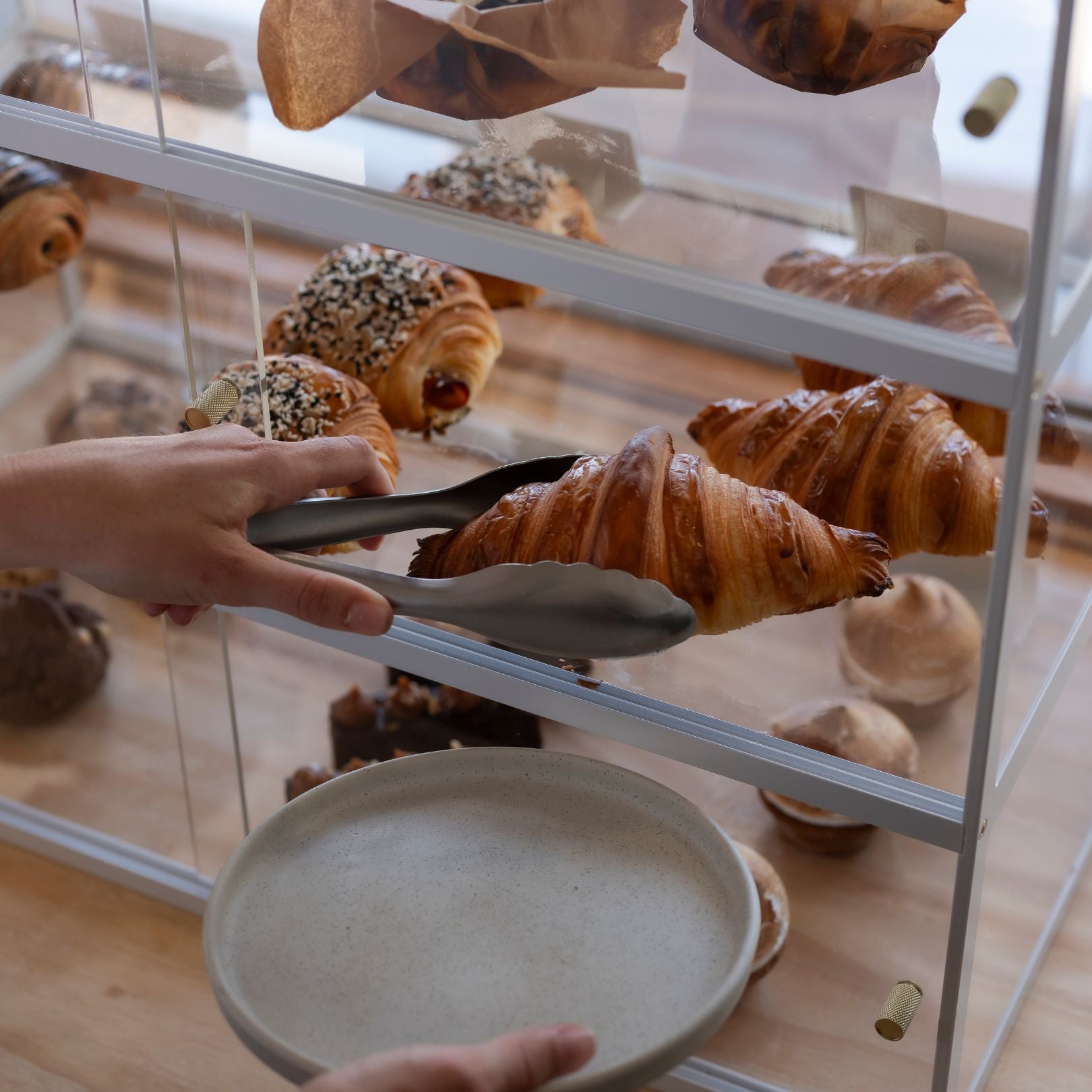 Person getting pastries from acrylic pastry display cabinet