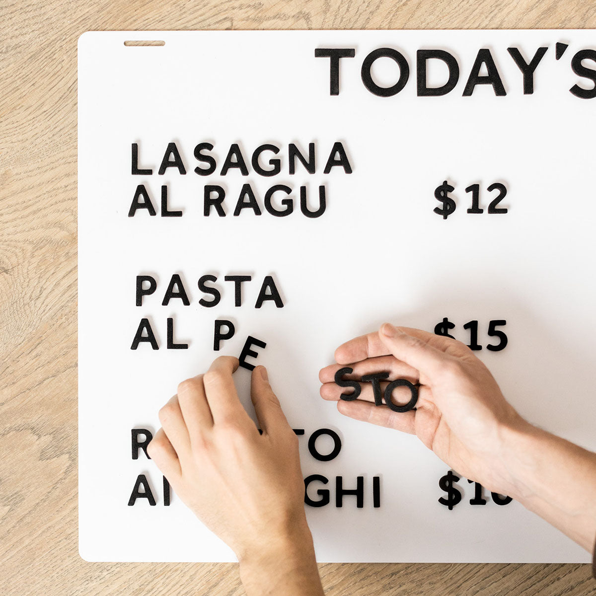 human applying magnetic letters to a hanging menu board 